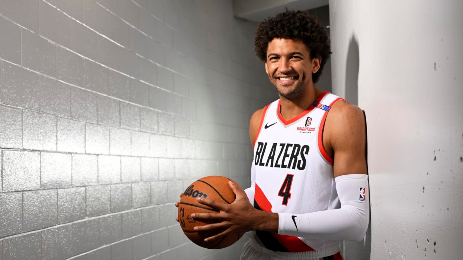 NBA star Matisse Thybulle wears a Blazers jersey and holds a basketball in a whi